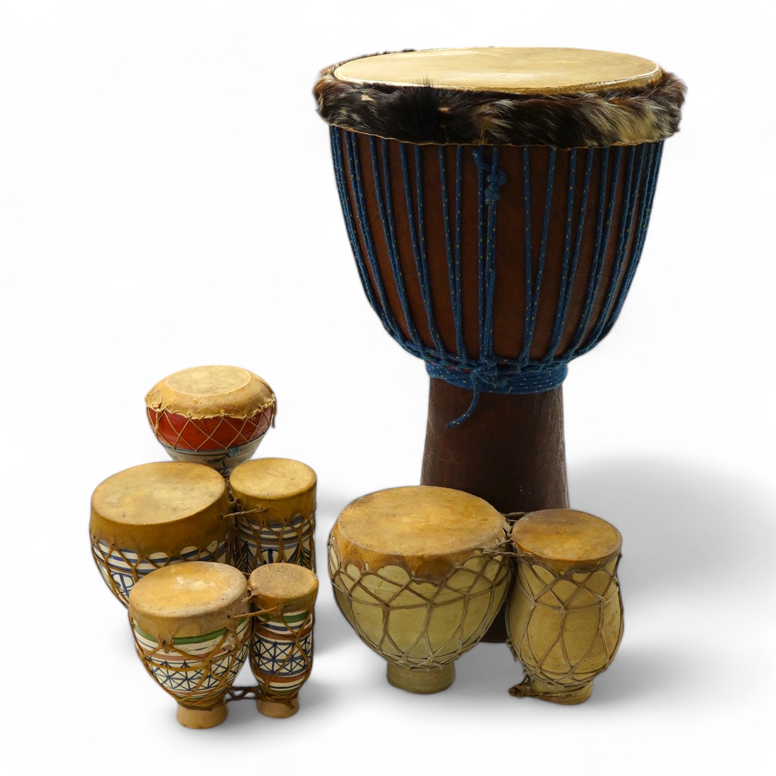 Five African drums; a Djembe, 60cm high, together with four small North African pottery double drums. Condition - fair to good.